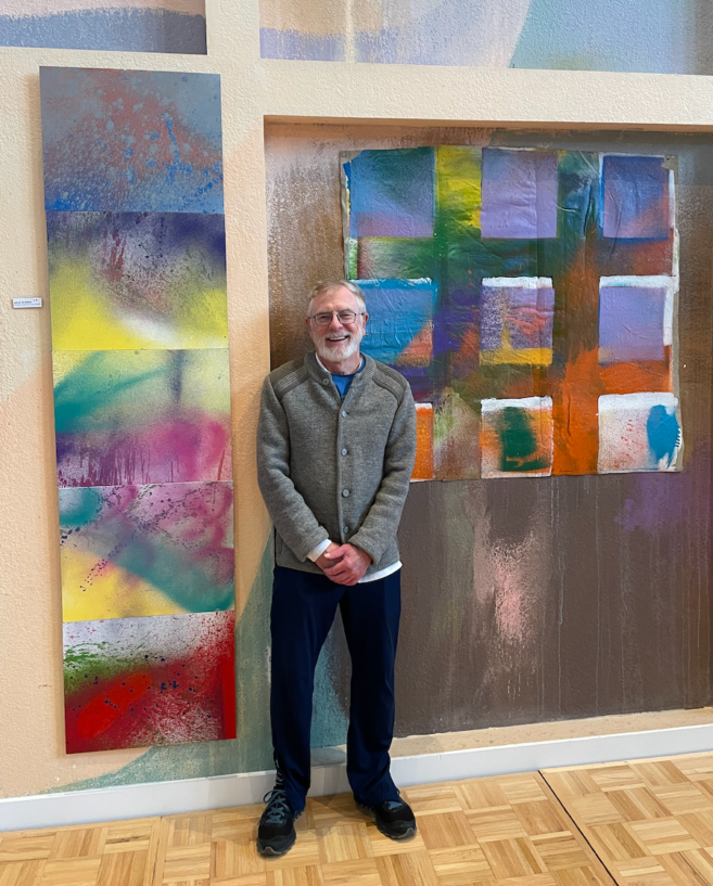 Photo of John A. Barry standing in front of two P6 works of art.