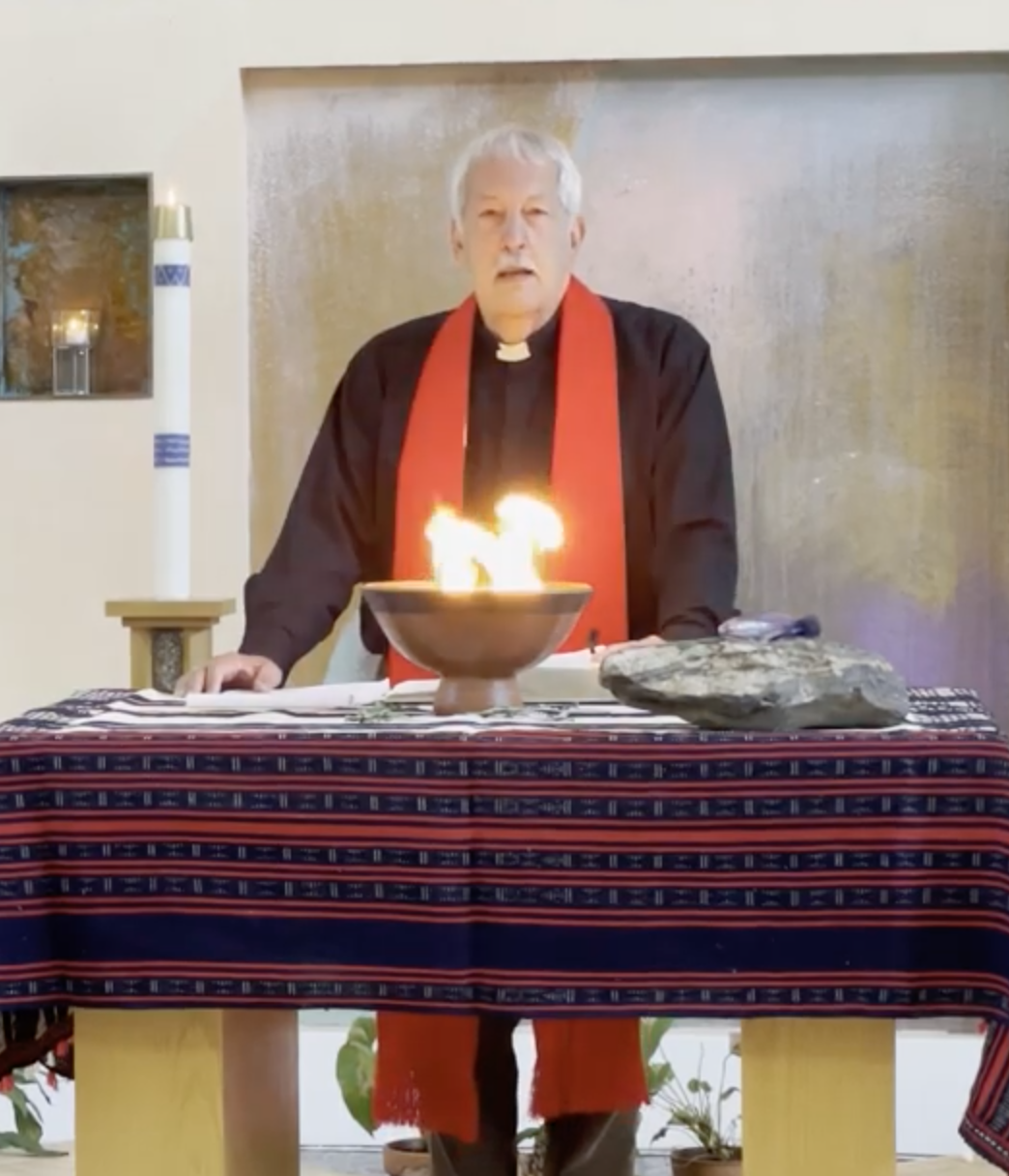 Photo of Pastor Steve Harms standing at the Peace Altar with the Fire of Pentecost.